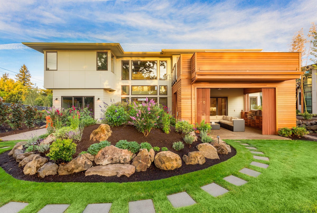 Modern home landscape with rock planting bed, stepping stones, and lawn