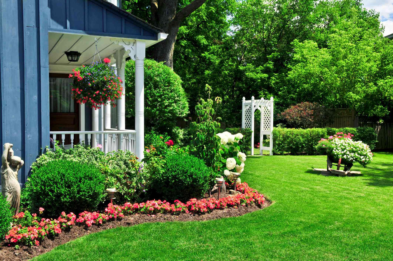 Landscaped front yard with flower beds, shrubs, and a green lawn
